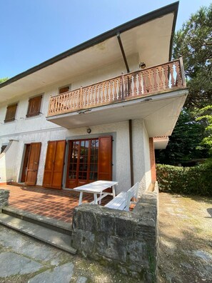 Un bâtiment à deux étages doté d’un balcon, d’un mur en pierre et d’une terrasse carrelée avec une table et des chaises.