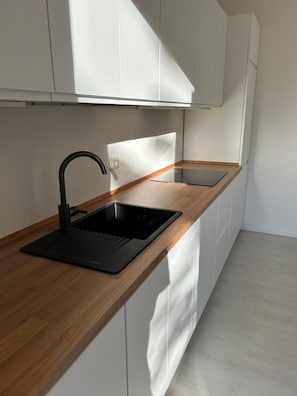 Une cuisine moderne avec un évier noir, un plan de travail en bois et des meubles blancs.