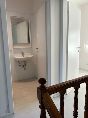 Une salle de bain avec un lavabo blanc, un miroir et un plancher en bois.