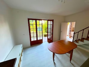 A spacious room with a wooden table, a staircase, and a sliding glass door leading to an outdoor area. - Casa la Pineta Poveromo vicino al mare con giardino privato (Massa)
