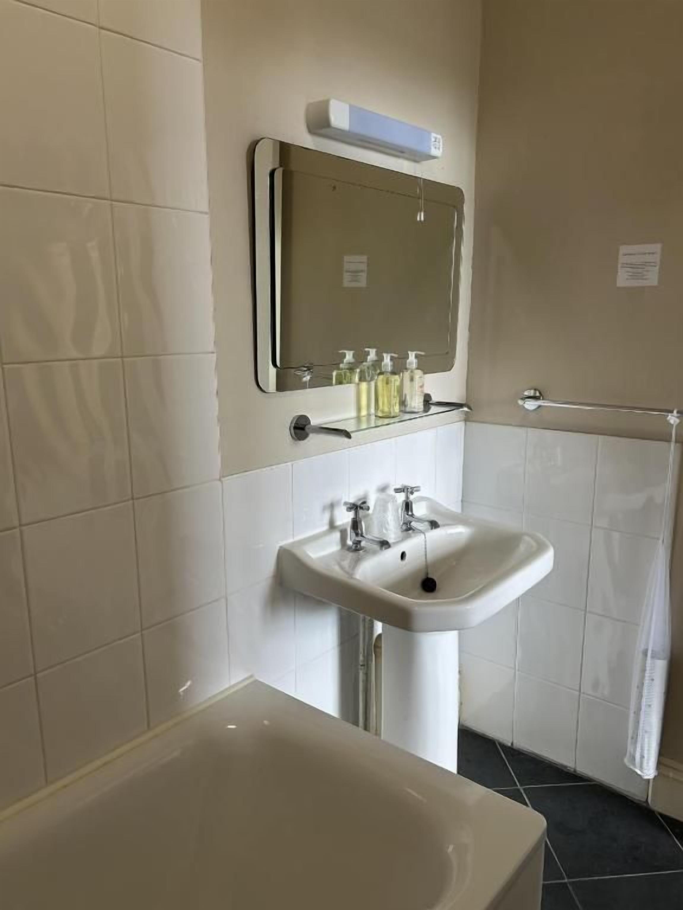Een badkamer met een bad, wastafel, spiegel en handdoekrek.