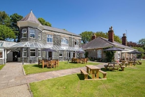 A stone building with a turret, outdoor seating, and a covered patio area. - Broadway Country House (Laugharne)