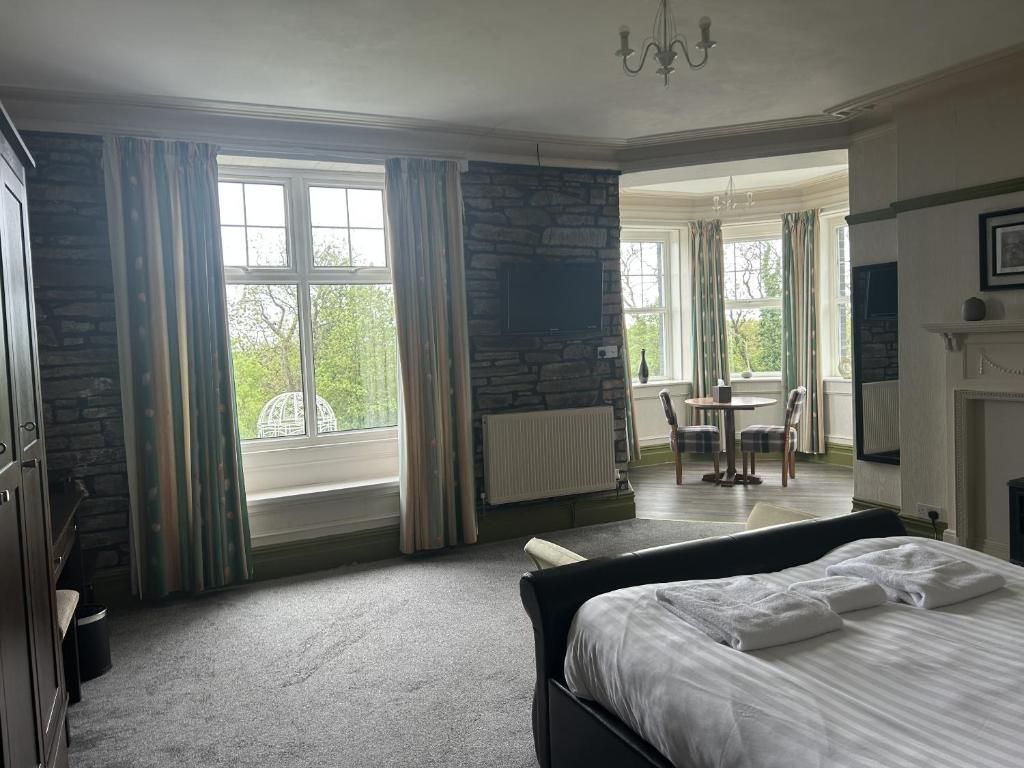 Een hotelkamer met een groot bed, een stenen muur, een open haard en uitzicht op het omliggende landschap.