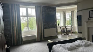Een hotelkamer met een groot bed, een stenen muur, een open haard en uitzicht op het omliggende landschap.