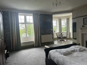 A hotel room with a large bed, a stone wall, a fireplace, and a view of the outdoors. - Broadway Country House (Laugharne)