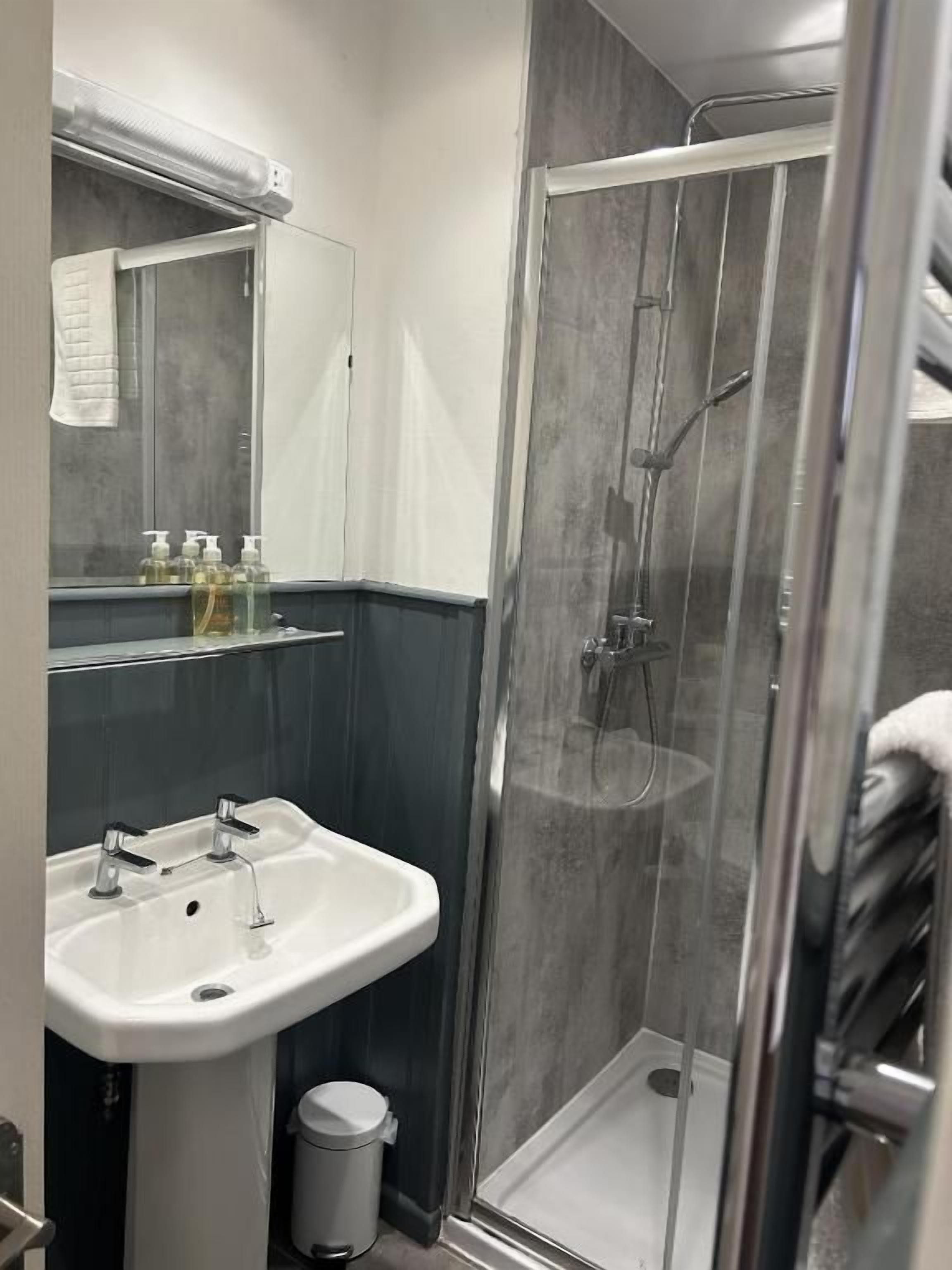 A modern bathroom with a glass-enclosed shower, a white sink, and a mirror above it.