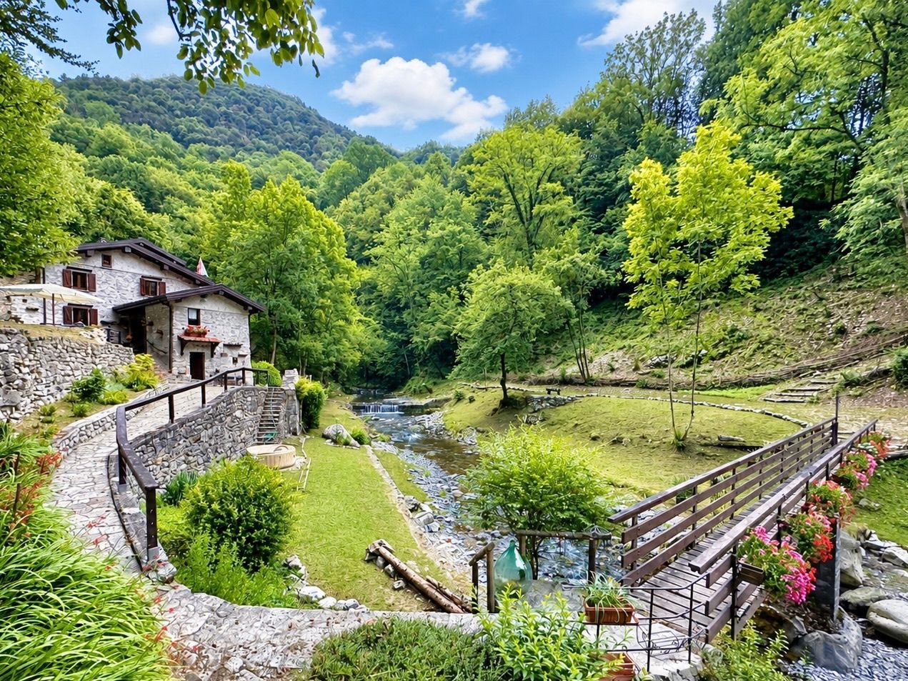 A stone house with a stone staircase leading to a wooden deck overlooking a river.