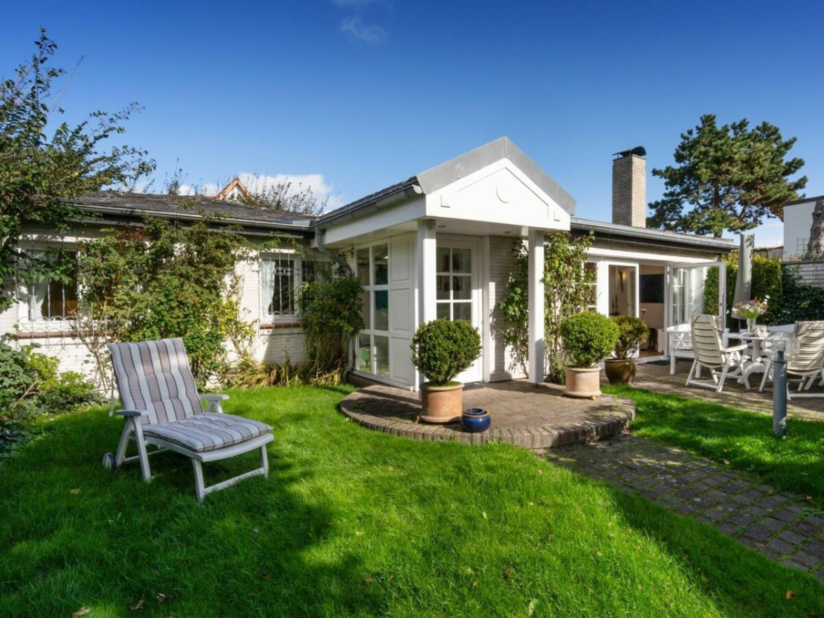 A house with a patio area, outdoor seating, and a garden.