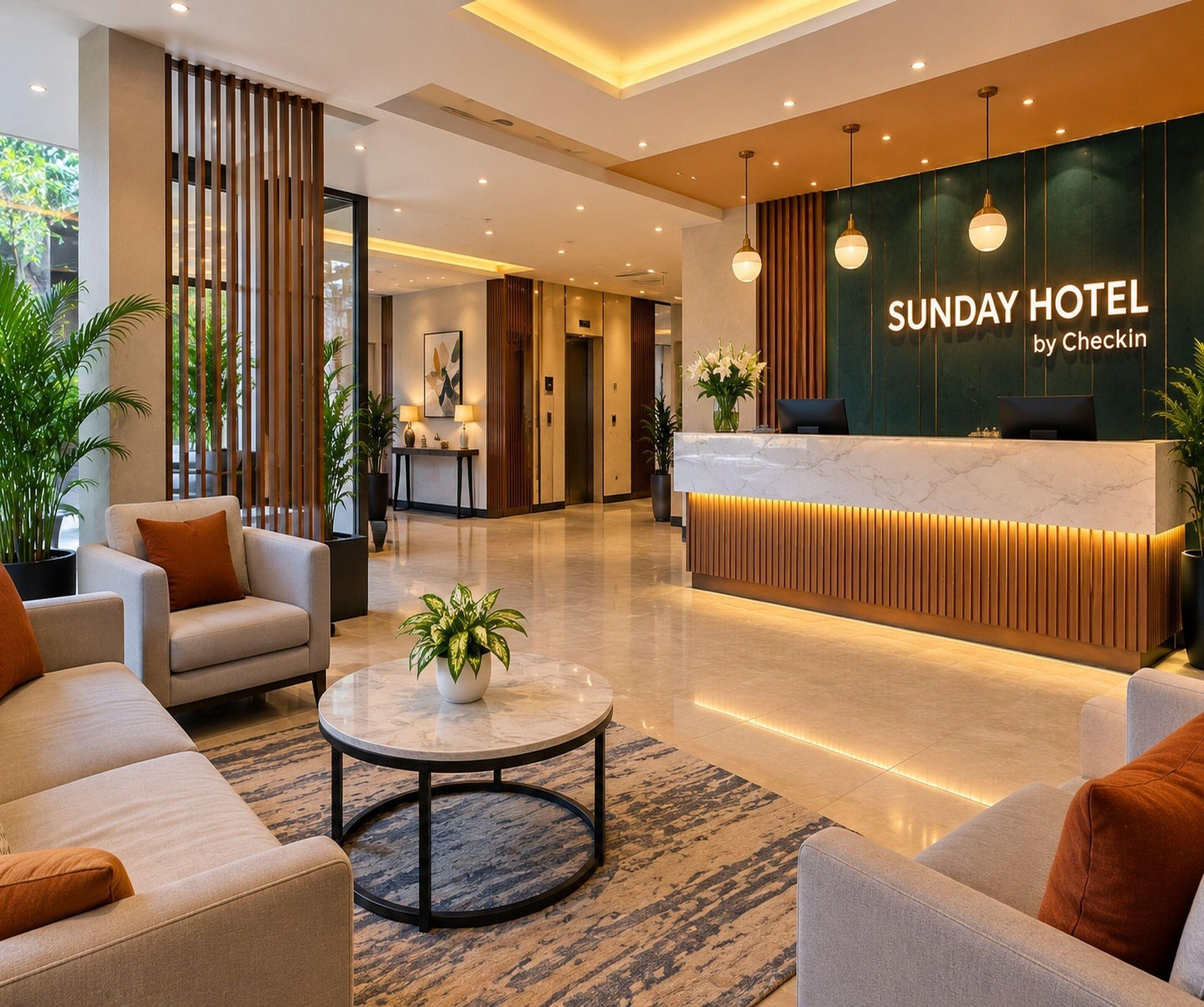 A hotel reception area with a modern design, including a reception desk, seating area, and a view of the hallway.