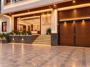 A hotel entrance with a reception desk, a staircase leading to the lobby, and a closed wooden door. - Hotel Radhe Elite At Delhi Airport  (New Delhi)