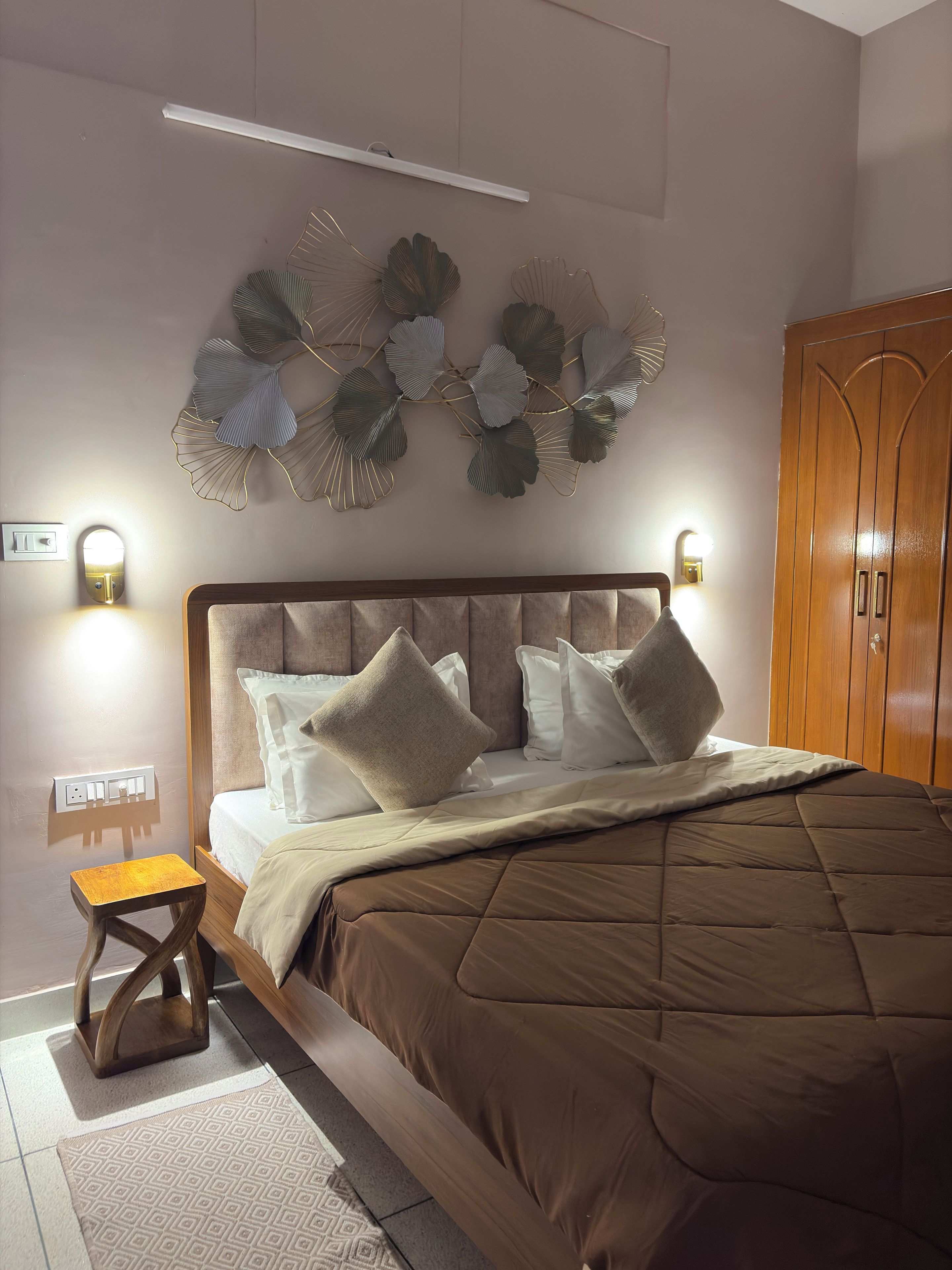 Un dormitorio con cama, mesitas de noche, lámparas fijadas a la pared y un elemento decorativo en la pared.