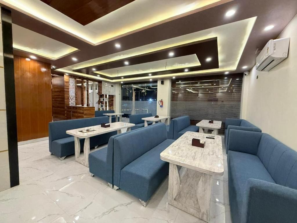 A modern lounge area with blue seating and marble tables, featuring a contemporary design with recessed lighting and a visible air conditioning unit.