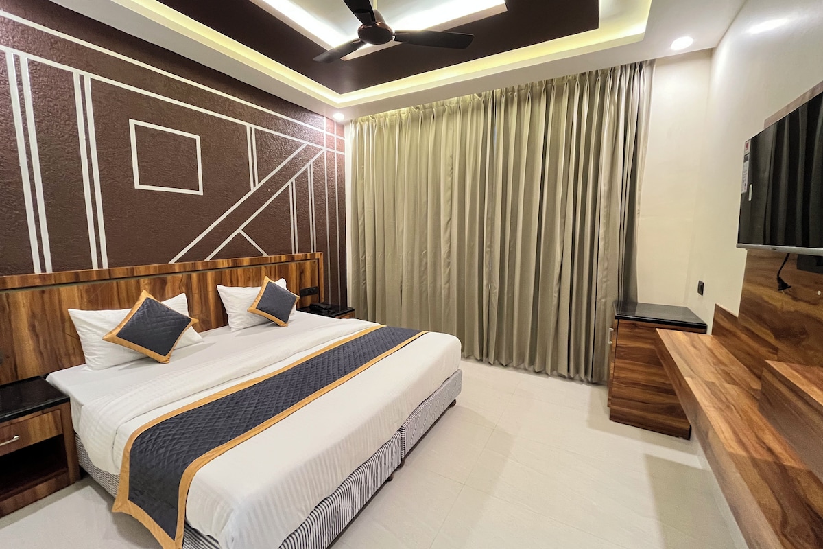 Een moderne hotelkamer met een groot bed, een houten hoofdbord, een flatscreen televisie en een plafondventilator.