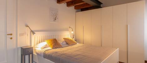 A bedroom with a bed, bedside tables, a wardrobe, and a ceiling with exposed beams.