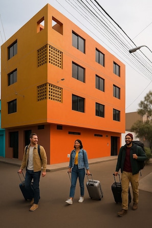 A modern building with a flat facade, multiple windows, and a visible power line. - Alojamiento Kely (Callao)