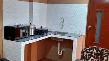 Une cuisine de taille réduite, équipée d’un évier, d’une cuisinière et d’un four à micro-ondes.