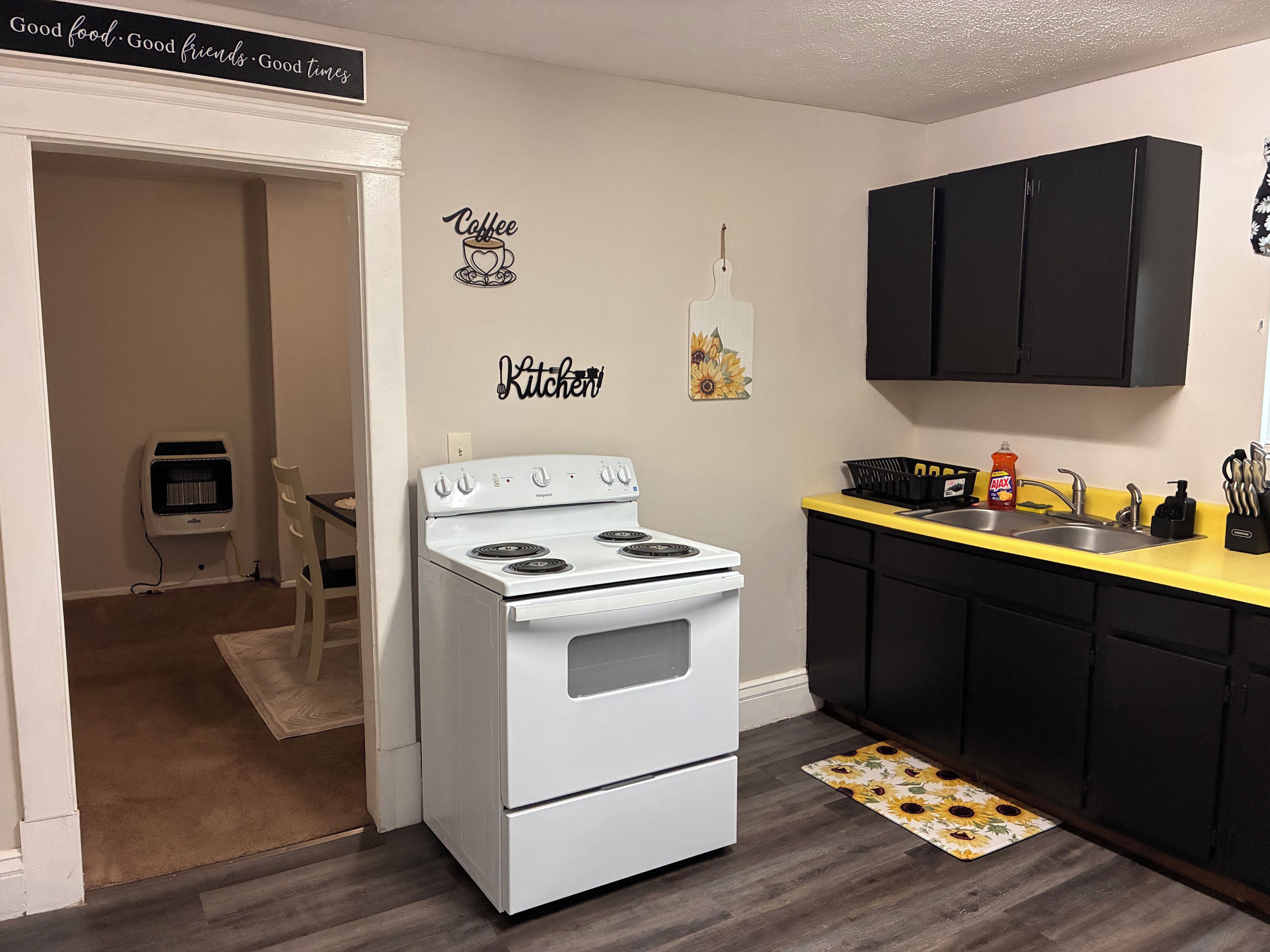 A kitchen with a white stove, black cabinets, and a yellow countertop.