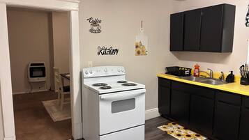 A kitchen with a white stove, black cabinets, and a yellow countertop.