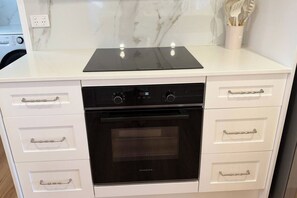 A kitchen with a built-in oven, a black stovetop, and white cabinetry with silver handles. - Holiday House Southport, GOLD COAST (Southport)