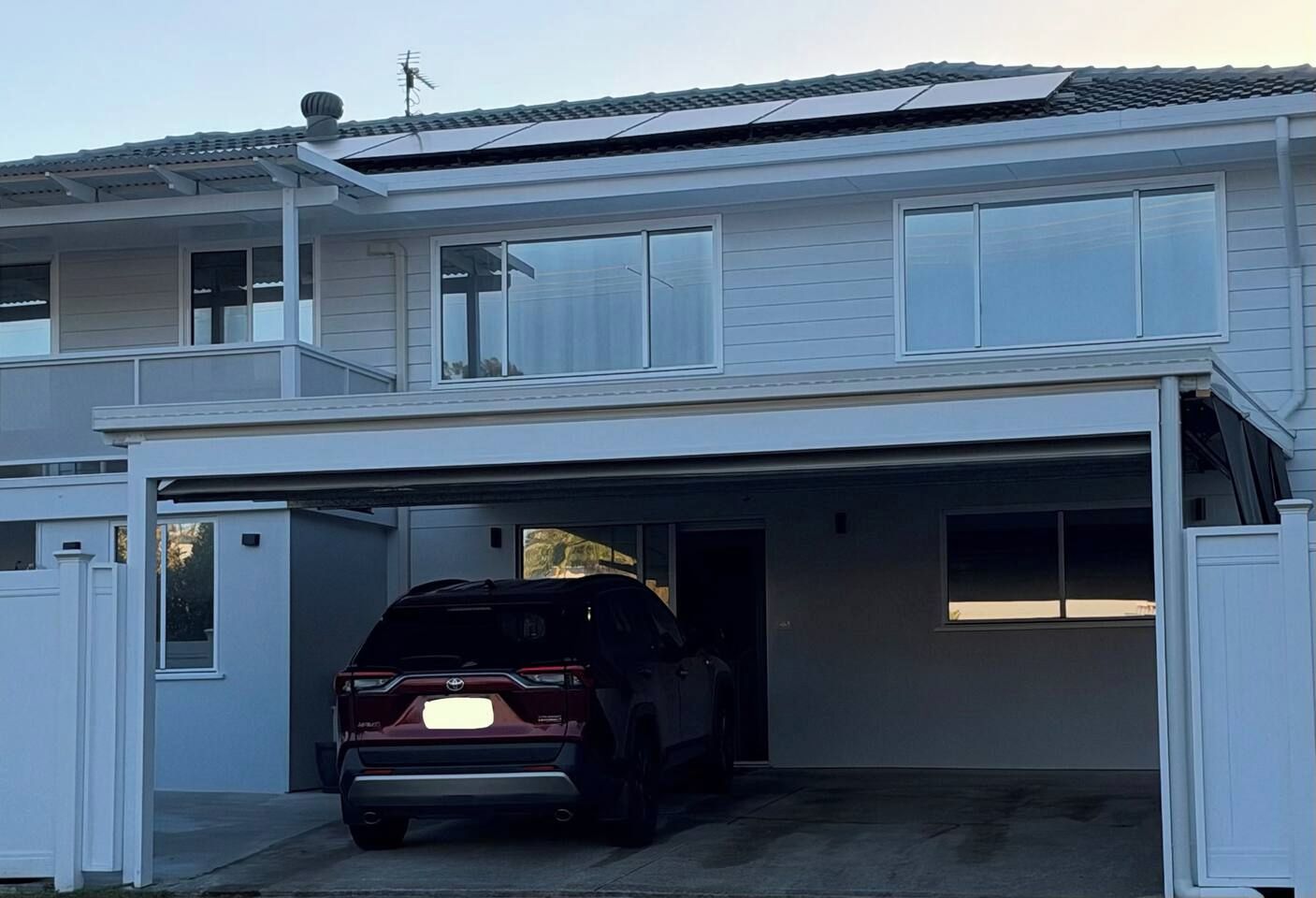 Et toetagers hus med en garageport, der er åben, og viser en mørk SUV parkeret indeni.