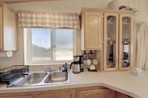 Une cuisine équipée d’un évier à deux bacs, d’une machine à café et d’un meuble avec des portes en verre.