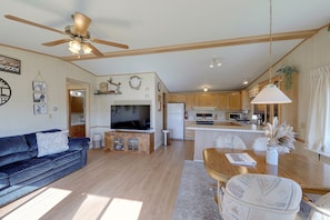 A spacious living area with a ceiling fan, a television, and a dining table with chairs. - Montana Mountain Escape! Views, Trails & Toys (Dupuyer)