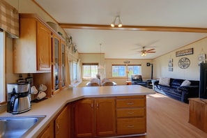 A spacious kitchen with wooden cabinets, a built-in island, and a large window. - Montana Mountain Escape! Views, Trails & Toys (Dupuyer)
