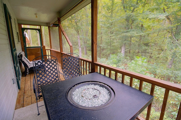 Una terraza con mesa y sillas, con vistas a un bosque.
