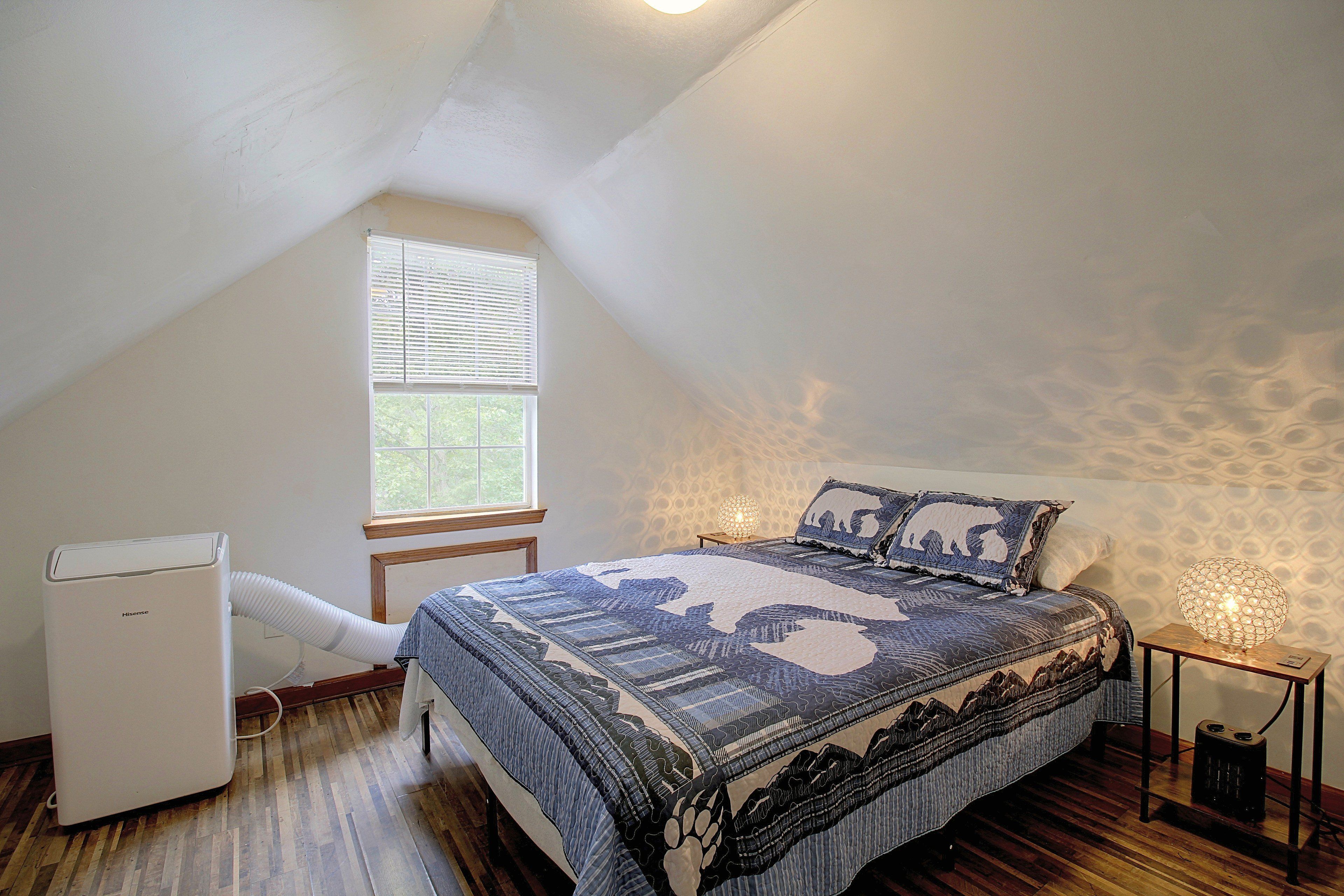 Un dormitorio con techo inclinado, una cama con ropa de cama estampada, un calentador, una ventana con persianas y una pared con textura.