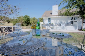 A glass table with wine glasses, a bottle, and a basket of lemons.