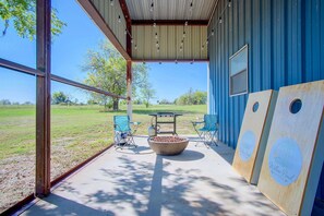 An outdoor patio area with a table, chairs, a fire pit, and a large wooden board with a logo.