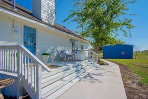 A single-story house with a covered porch, a blue door, and a small shed in the background.