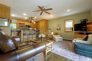 A spacious living room with a leather sofa, a coffee table, and a TV.