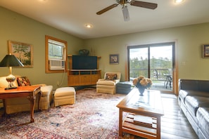 A living room with a ceiling fan, a television, a fireplace, and a large window.