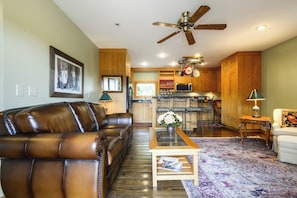 A living room with a brown leather sofa, a coffee table, and a ceiling fan.
