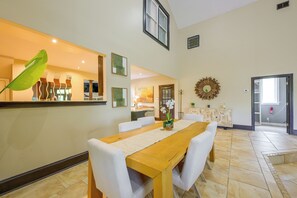 A dining area with a wooden table, white chairs, and a decorative mirror.