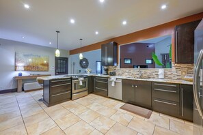 A modern kitchen with a central island, stainless steel appliances, and a decorative backsplash.