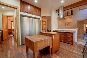 A kitchen with wooden cabinets, a stainless steel refrigerator, a wooden island, and a stone accent.