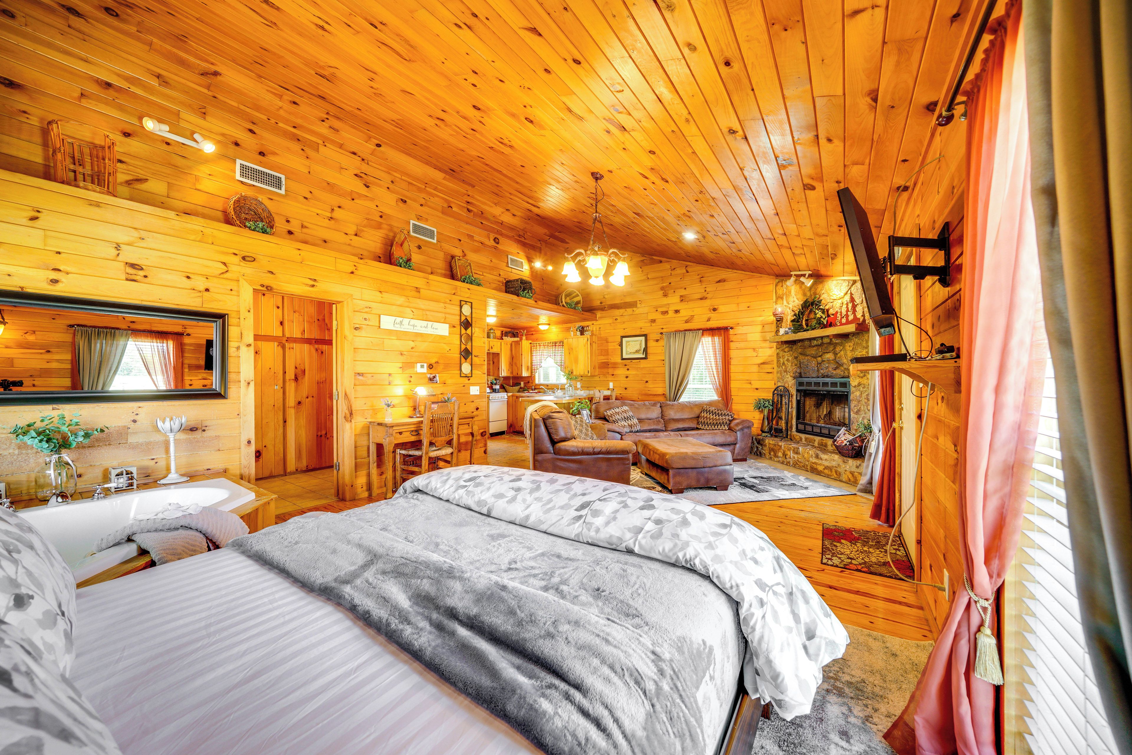 A cozy log cabin with a large bed, a fireplace, and a dining area.