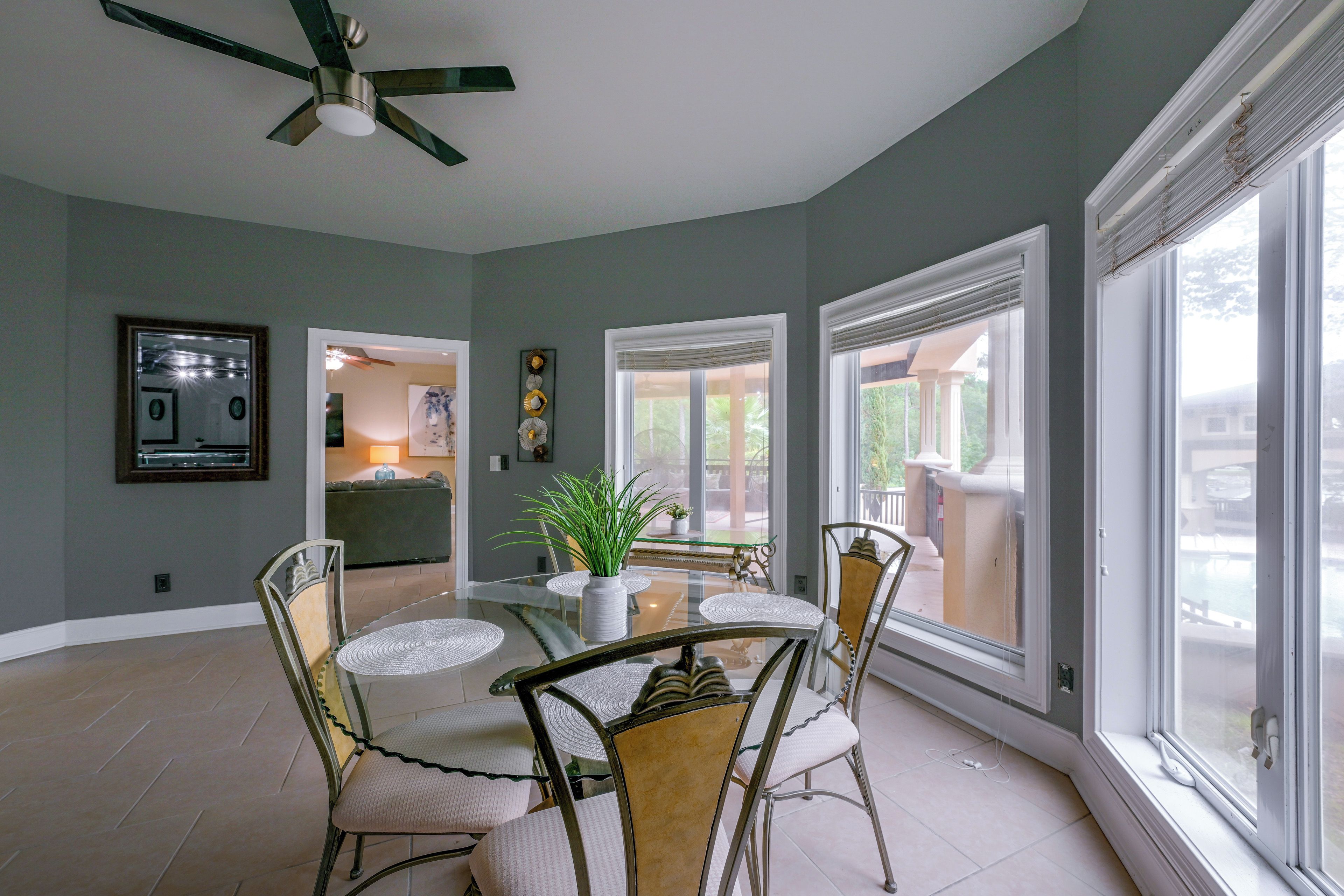 A dining area with a glass table, chairs, and a ceiling fan.