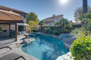A residential property with a swimming pool, outdoor furniture, and a covered patio area.