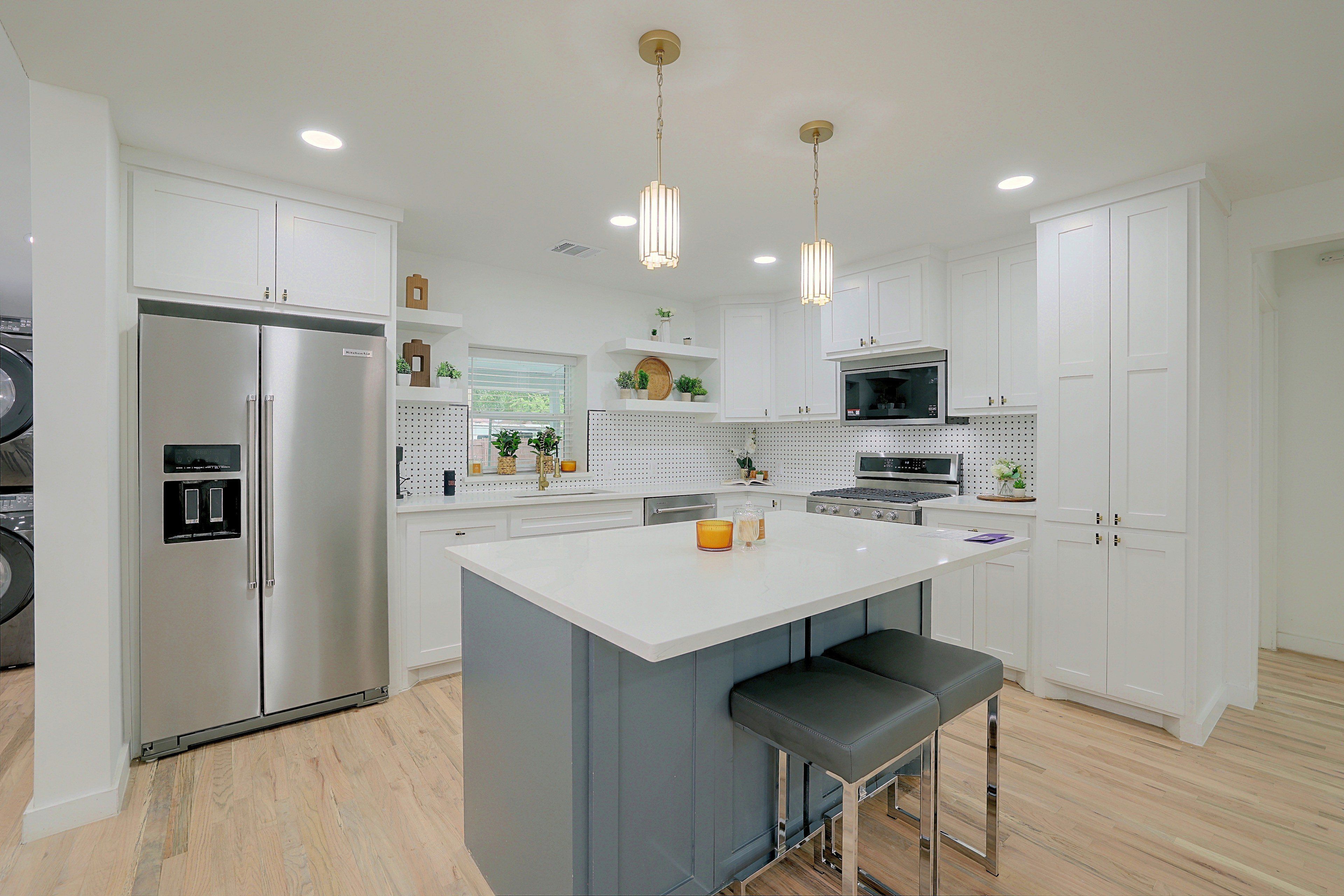 A modern kitchen with a central island, stainless steel appliances, and pendant lighting.