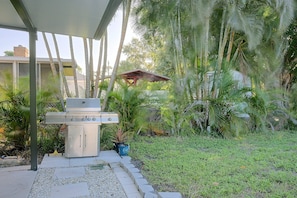 An outdoor grill area with a covered patio, surrounded by lush greenery and a fence. - Paradise Del Sol by Gulf Beaches: Endless Summer! (Nokomis)