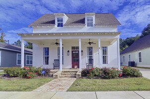 A two-story house with a covered porch, two windows on the upper floor, and a red door.