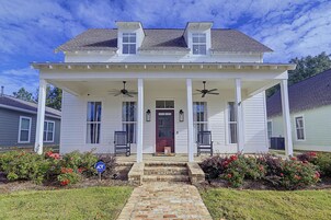 A two-story house with a covered porch, two windows on the upper floor, and a front door.