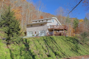 A two-story house with a garage, a covered porch, and a hillside setting.