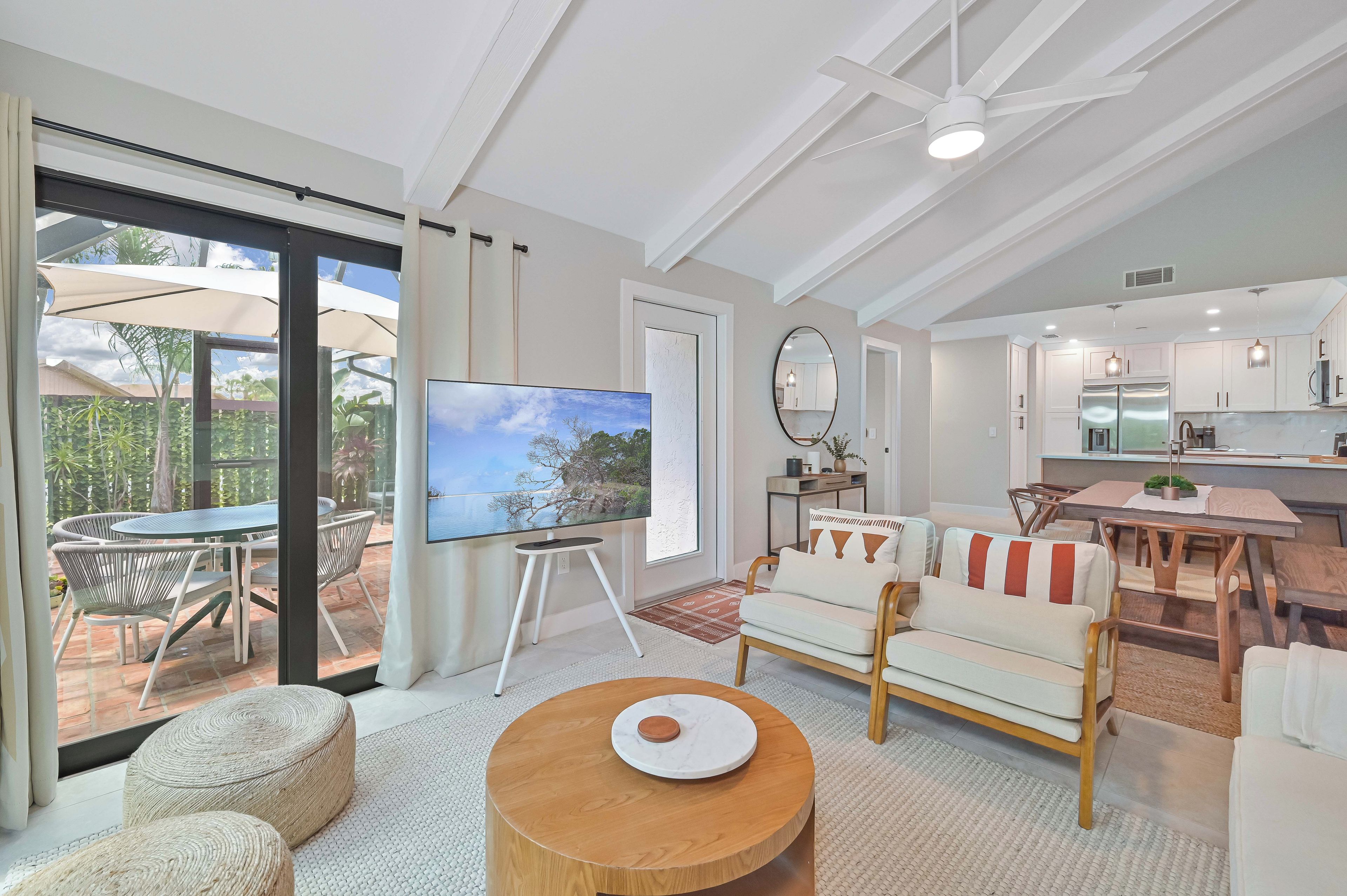 A spacious living area with a large TV, comfortable seating, a dining area, and a kitchen.