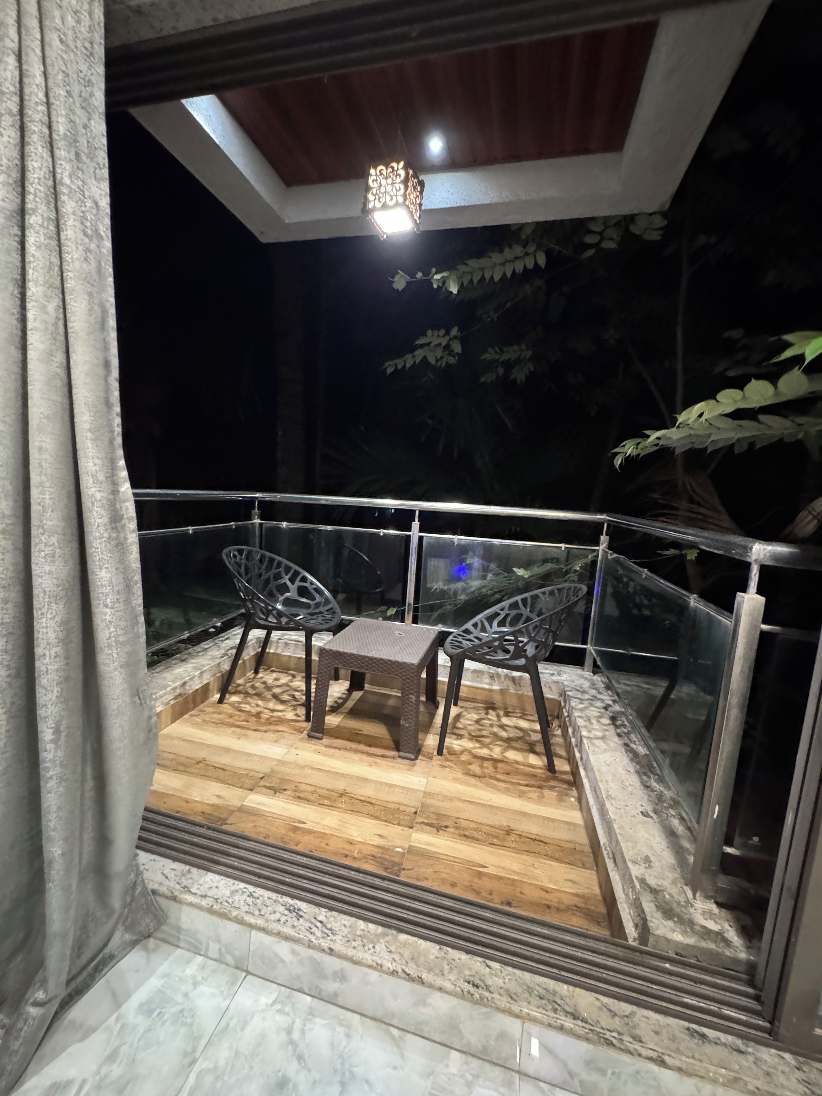 A balcony with a table and chairs, a glass railing, and a ceiling light.