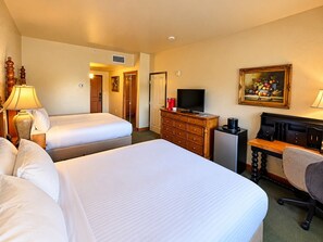 A hotel room with two beds, a desk with a computer, a television, and a painting on the wall.
