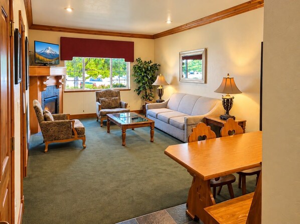 A cozy living room with a fireplace, comfortable seating, and a view of the outdoors.